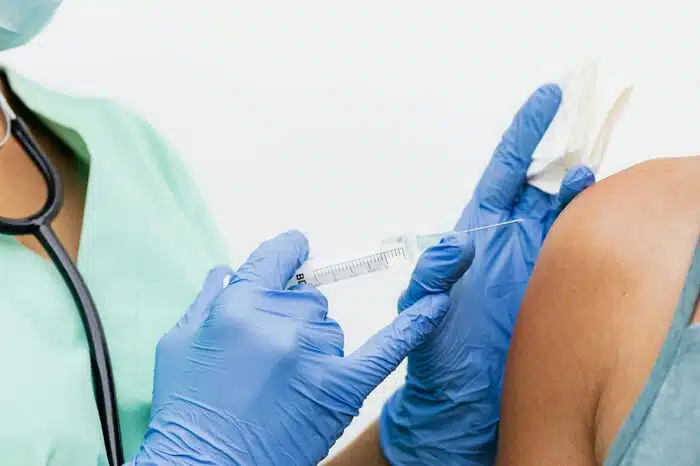A woman wearing a sleeveless shirt to receive a flu shot