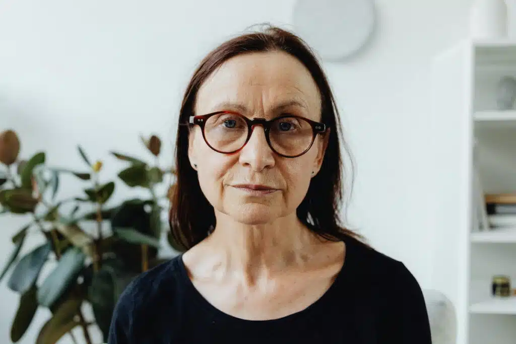 An Elderly Woman Wearing Red Framed Eyeglasses while Seriously Looking at the Camera